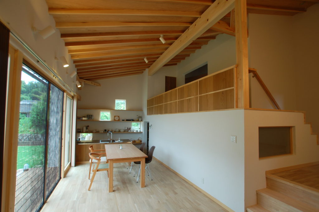 白い板張りソリッドな形状に木製格子が特徴的な人々が集うカフェスタイルの家