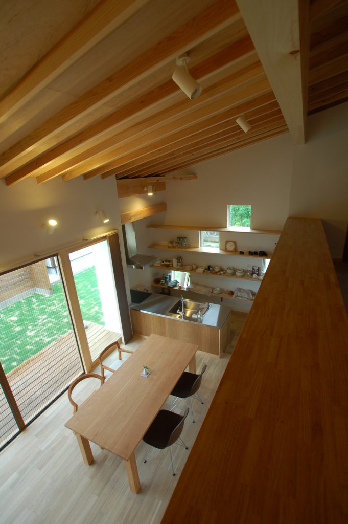 白い板張りソリッドな形状に木製格子が特徴的な人々が集うカフェスタイルの家
